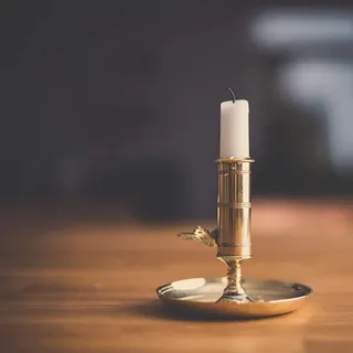 A brass chamberstick candle holder with a white candle