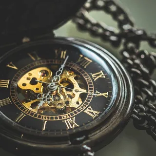 A black skeleton pocket watch on a chain