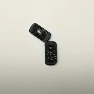 A black flip phone with a cracked screen