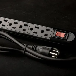 A black six-outlet power strip with its cord coiled