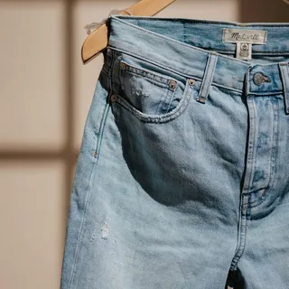 Light-wash jeans on a wooden hanger
